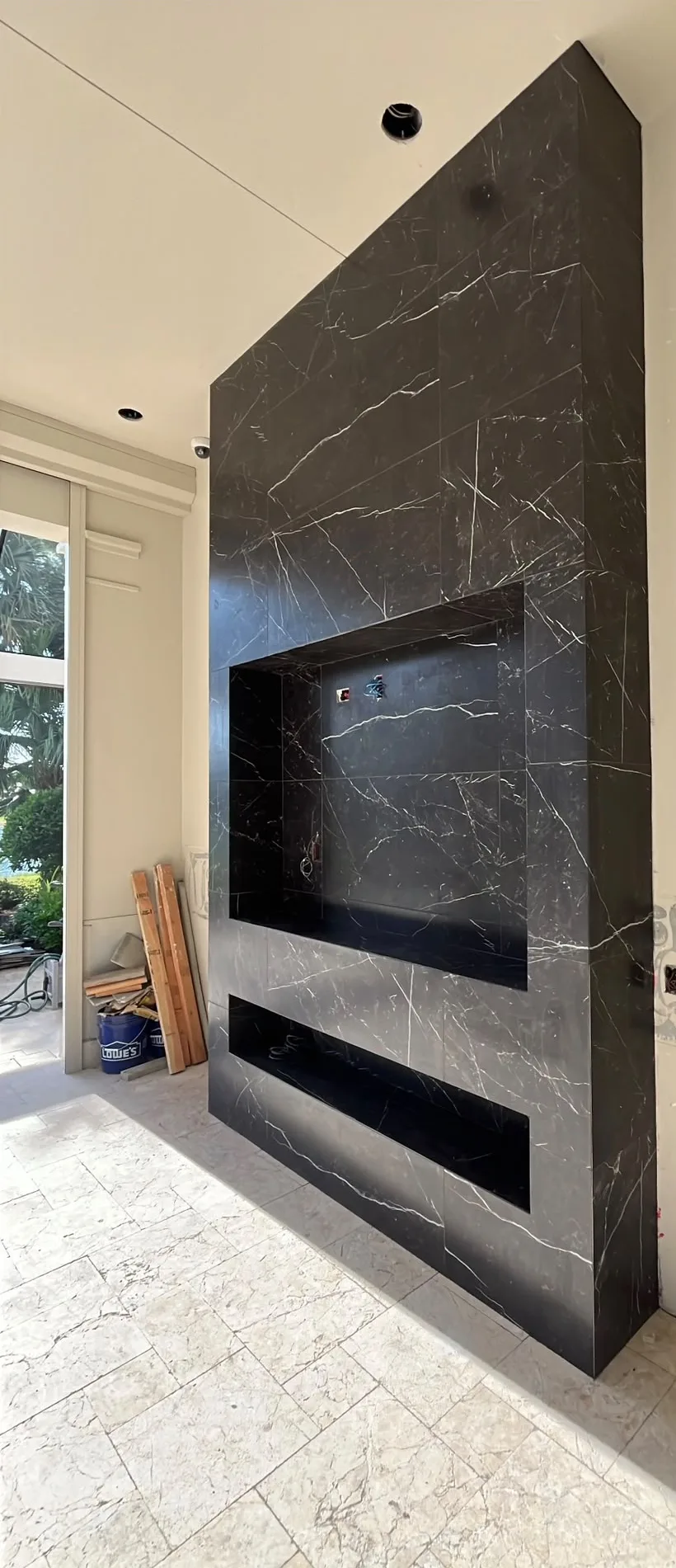 Floor-to-ceiling black marble-look porcelain fireplace wall with recessed TV niche and linear fireplace opening