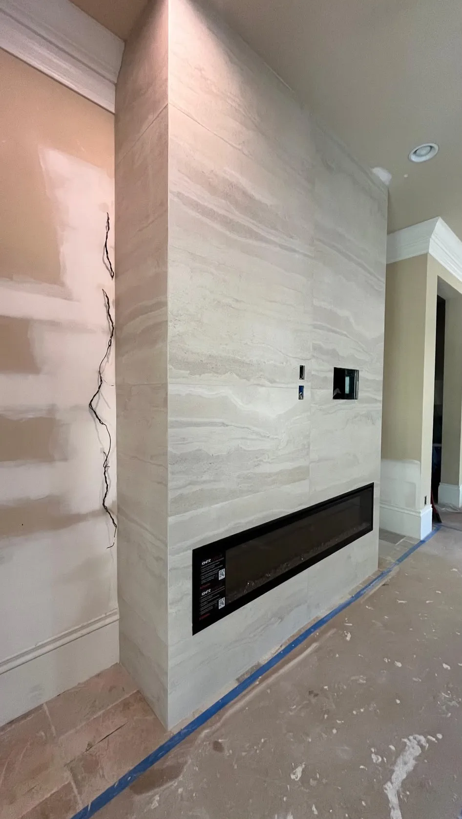 Floor-to-ceiling light travertine-look porcelain fireplace wall with a linear electric fireplace